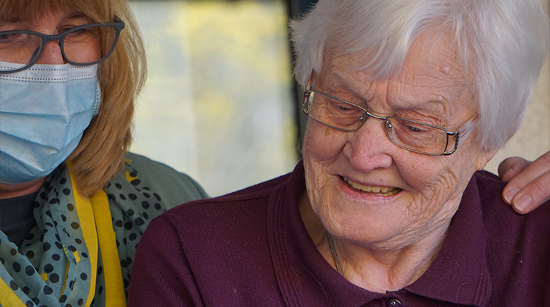 Resident and Staff Smiling at Image on Phone