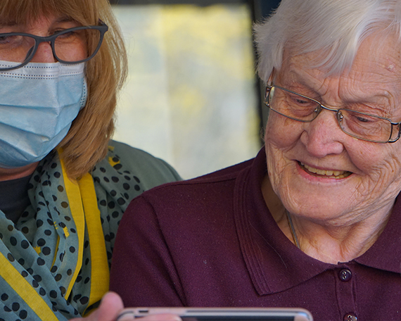Resident and Staff Smiling at Image on Phone