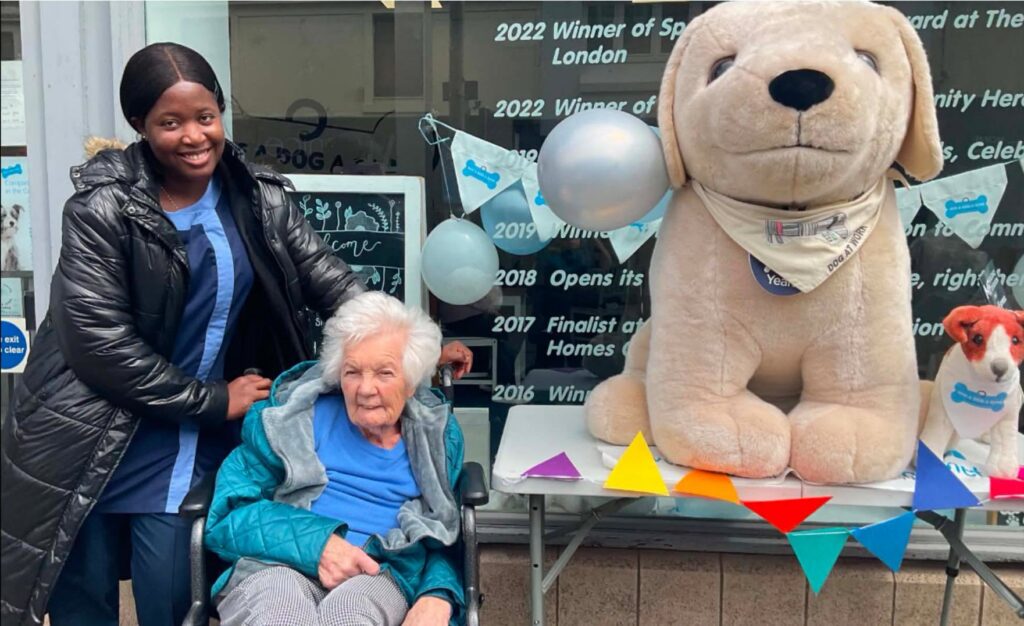 older lady and a carer by a charity table for service dogs