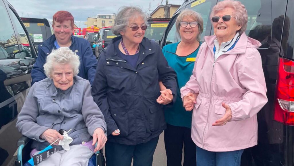 older ladies and carers by a taxi